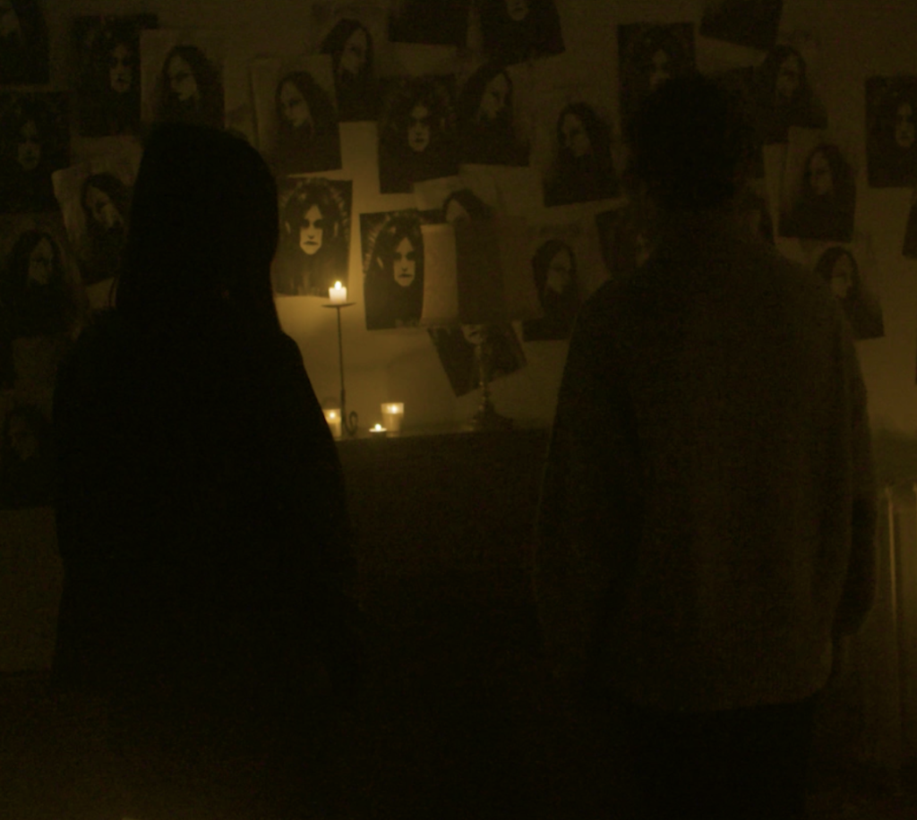 Une image du court métrage "La fille aux iris noires" où les deux protagonistes sont de dos dans le noir et éclairent le mur devant elles.